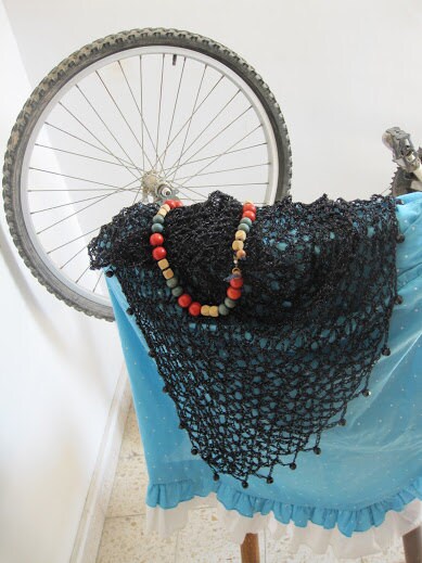 Black beaded shawl on a blue dress, photographed with a bicycle wheel in the background.
