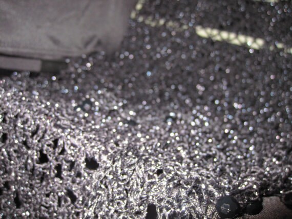 Close-up of the black lurex crochet texture, glittering stitches catching the light.