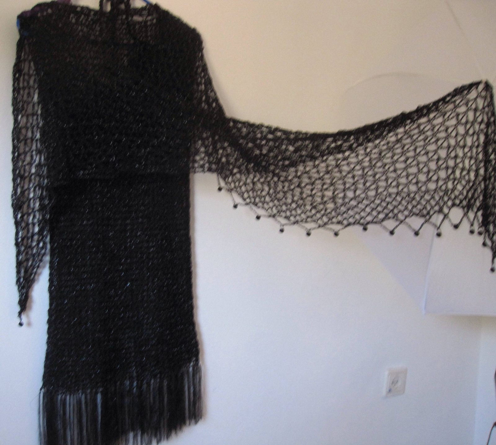 Black shawl spread wide over a black dress, full view of the airy openwork pattern.