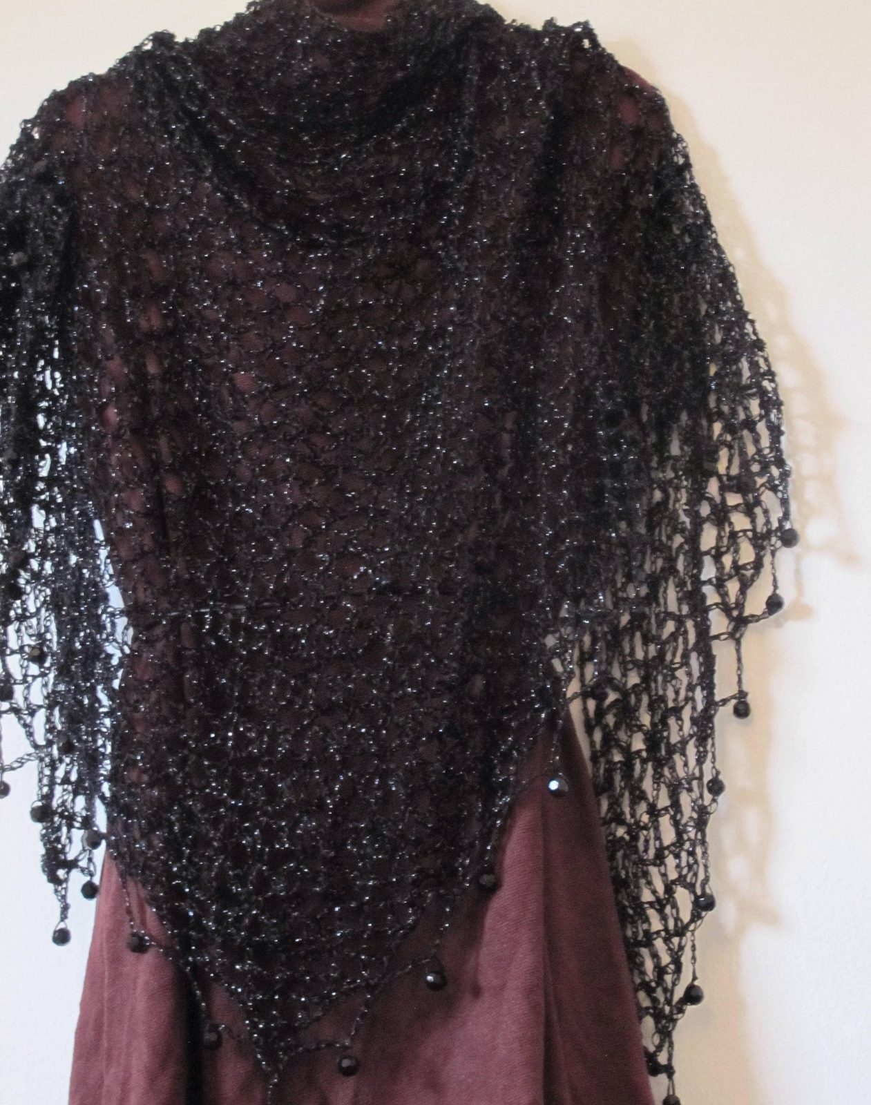 Black lurex shawl draped over a burgundy dress, front view of the sparkling wrap and beaded trim.
