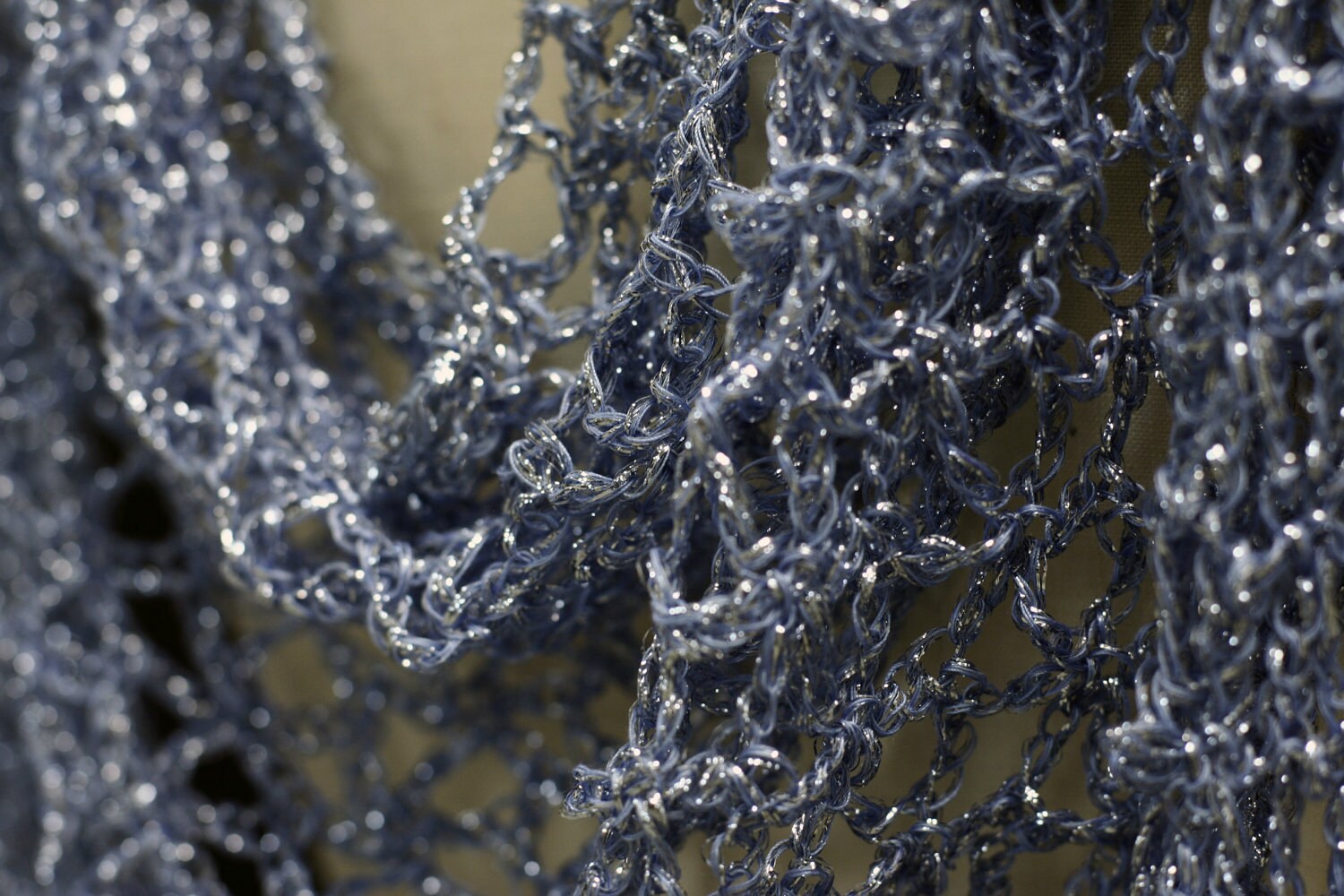 Close-up of the blue lurex crochet texture, sparkling hand stitches in fine detail.