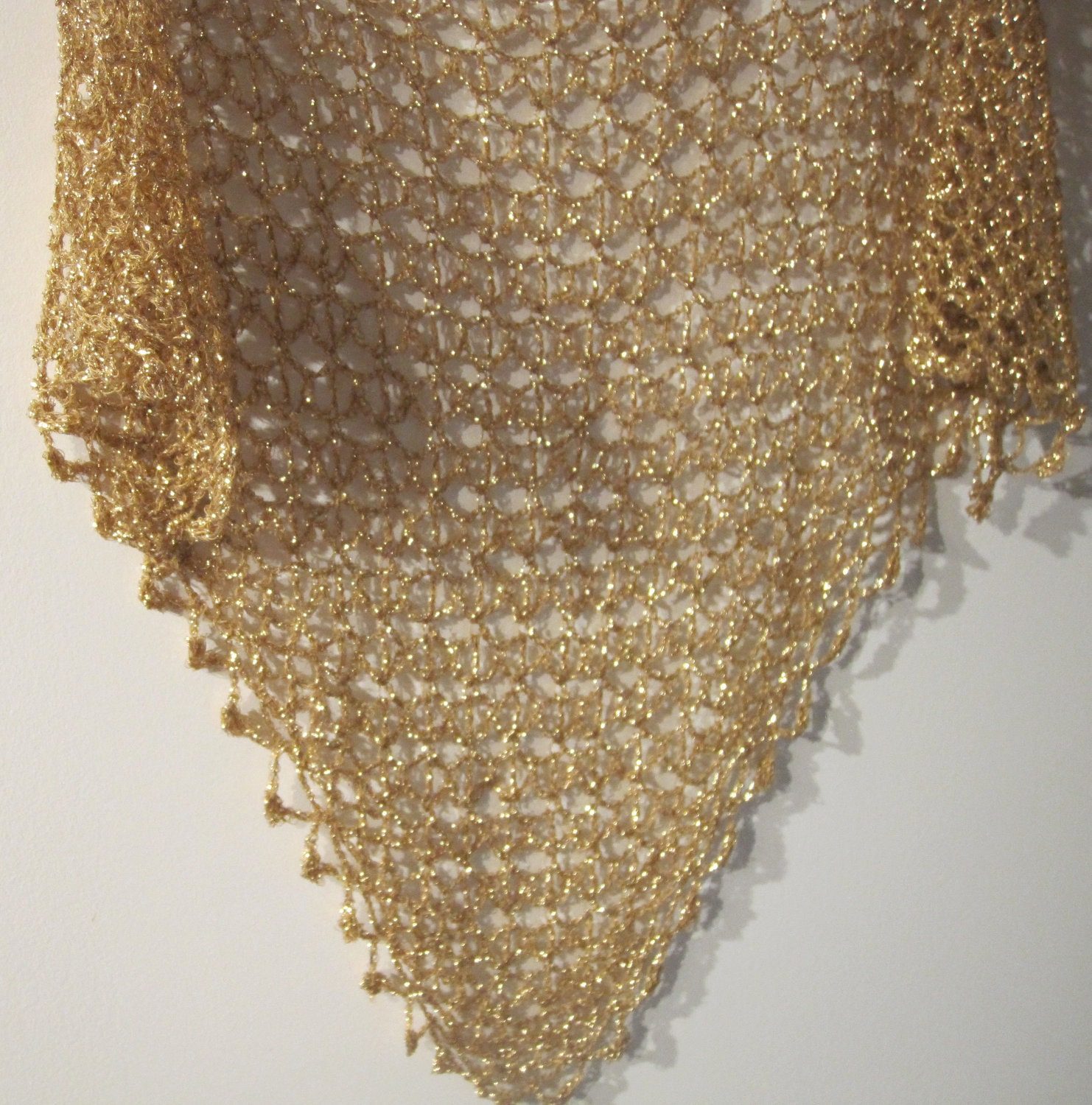 Champagne shawl hanging flat, full triangular view of the even openwork crochet.