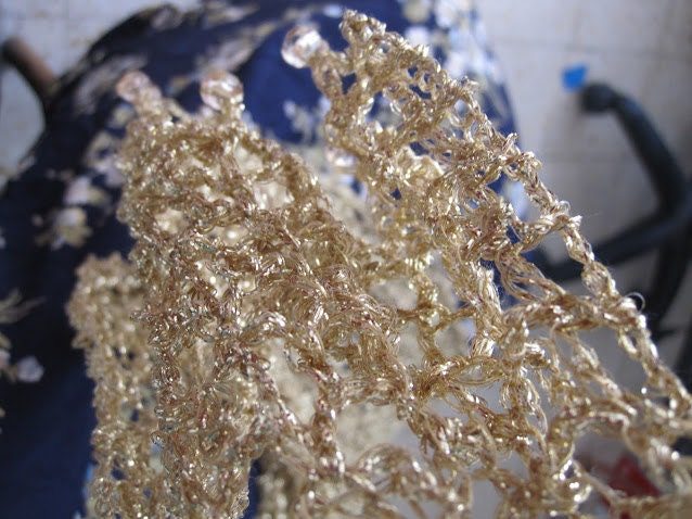 Close-up of the champagne lurex crochet texture, golden stitches glowing in the light.