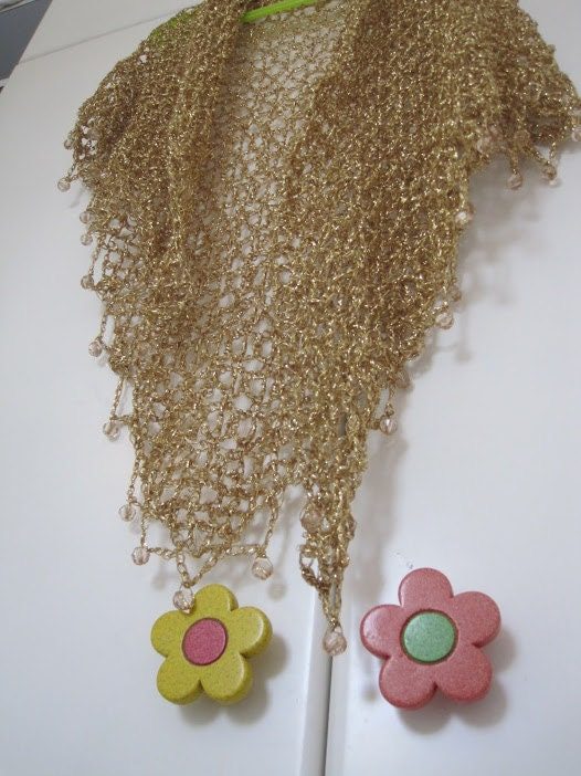 Champagne gold shawl on a white door with flower-shaped knobs, full view of the sparkling wrap.