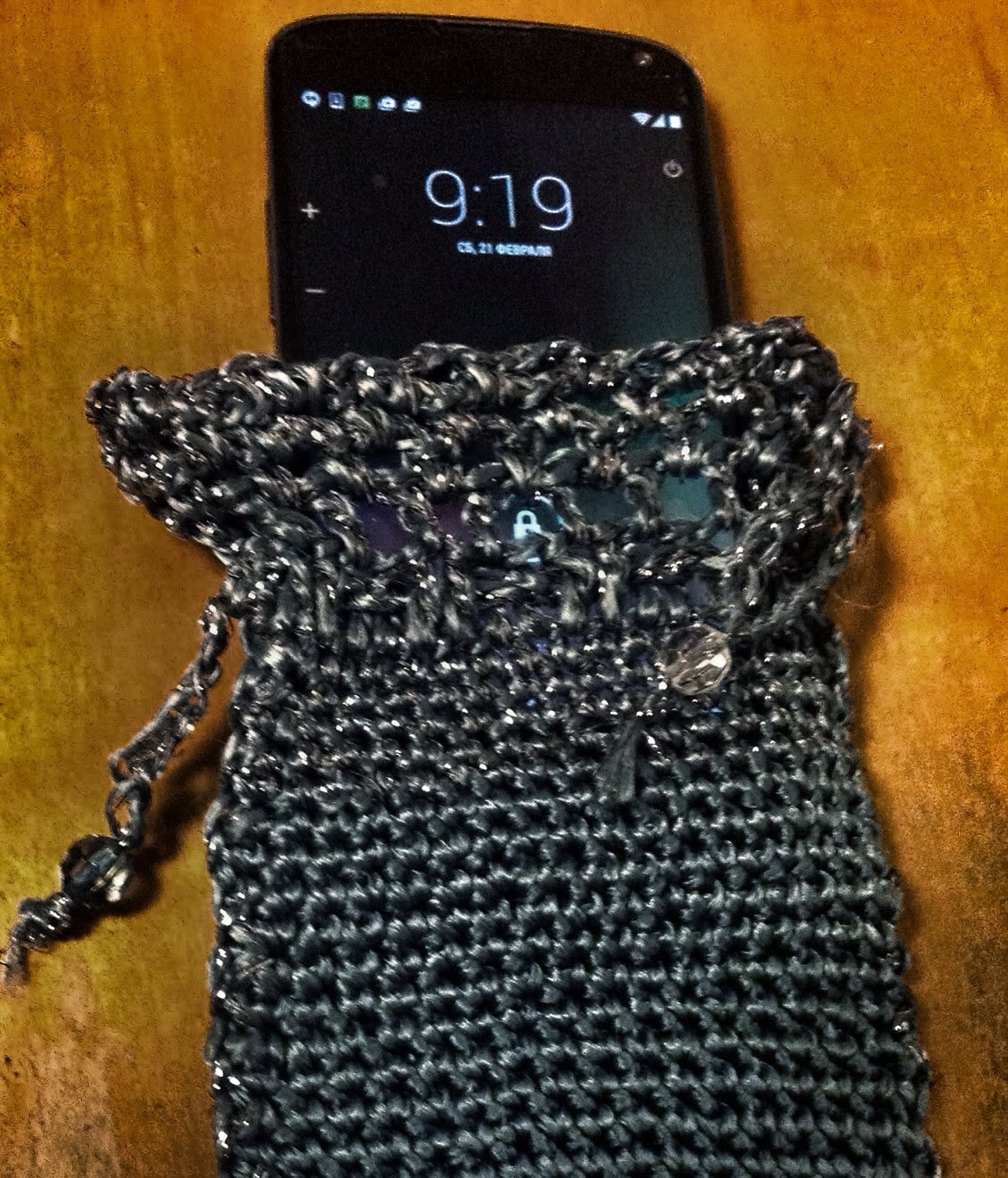 Grey crochet clutch bag holding a smartphone, showing the phone fits snugly inside the beaded evening purse.