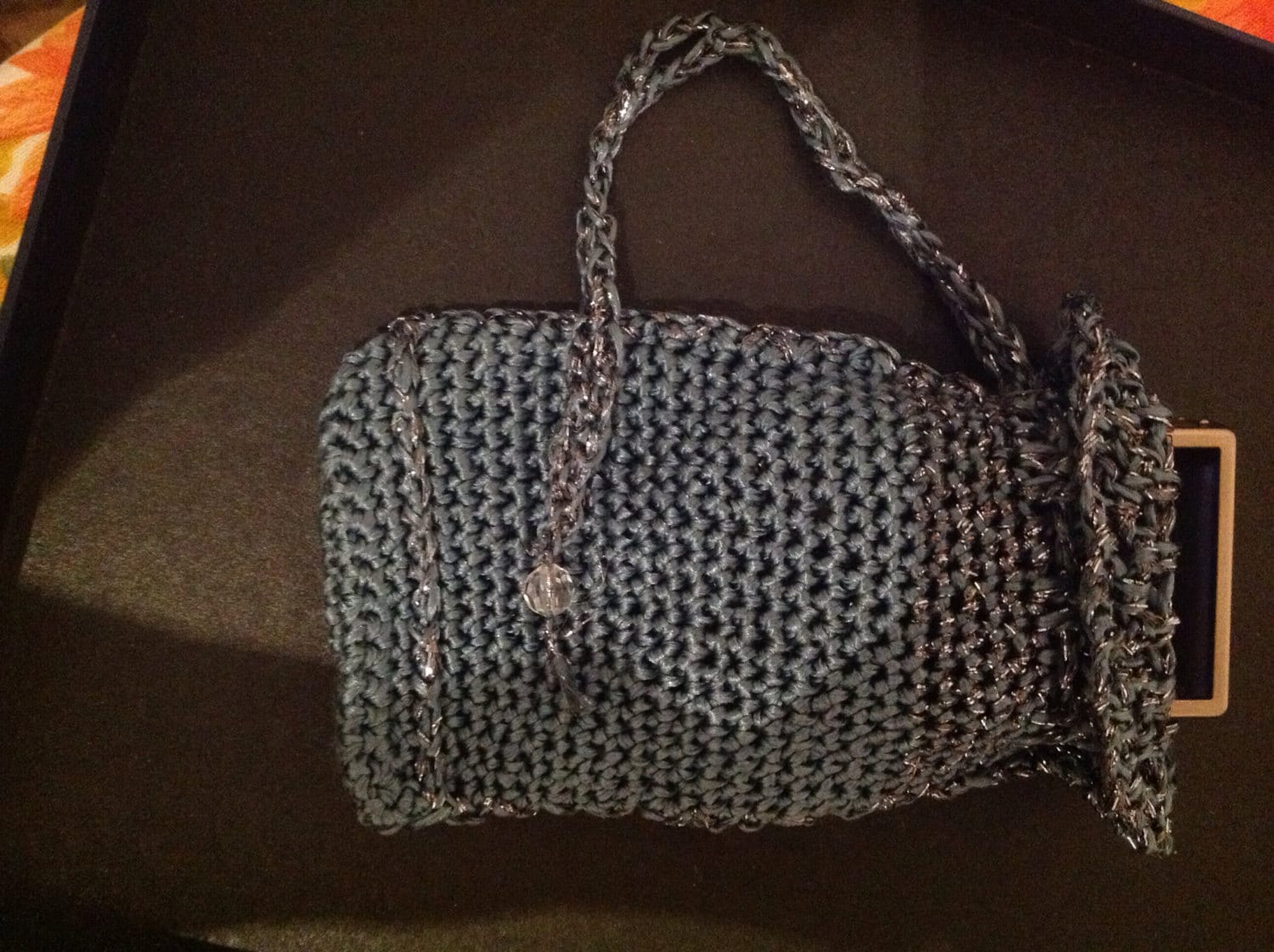 Grey crochet clutch with its strap extended, top view of the beaded evening bag.