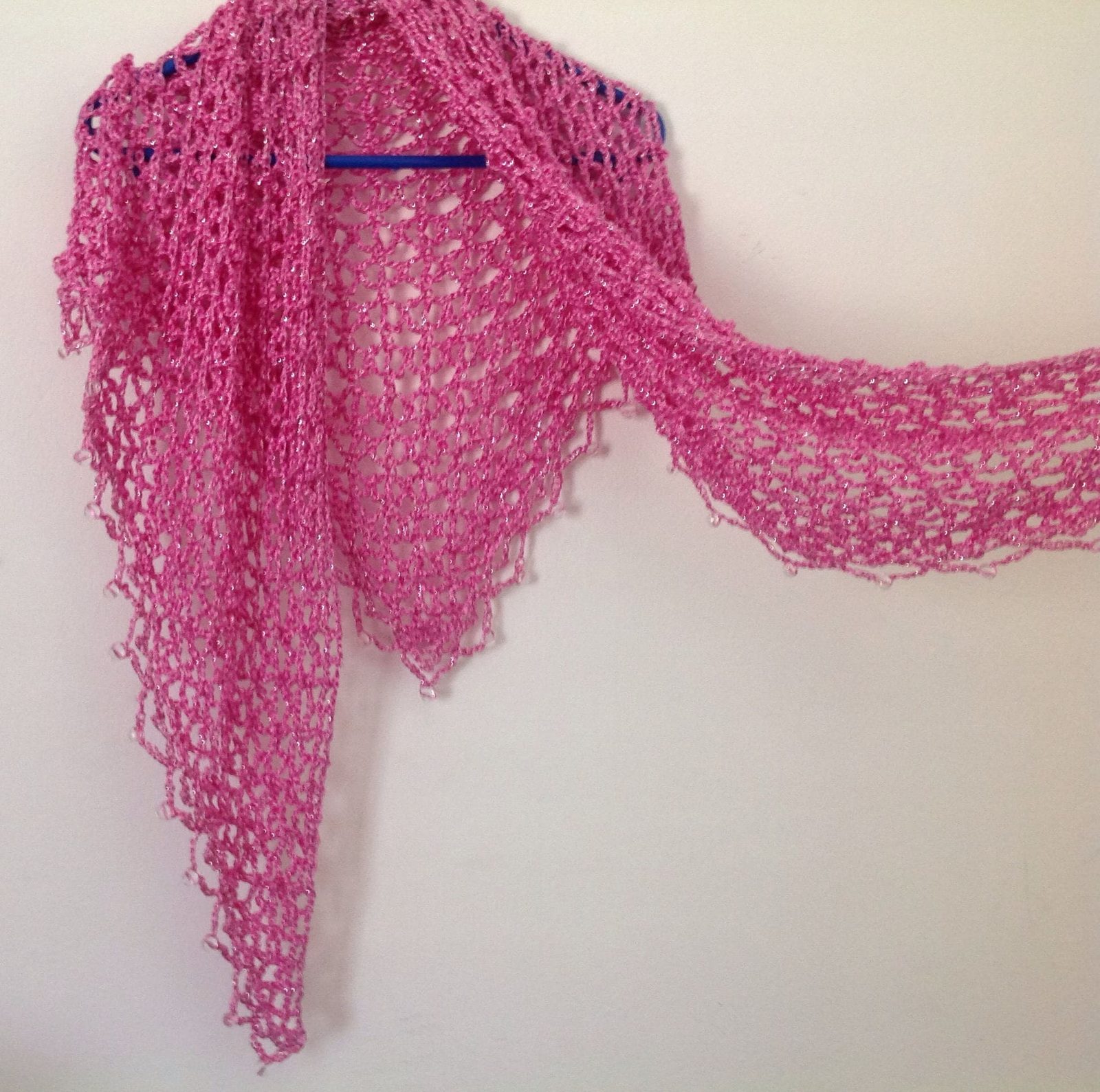 Pink shawl with one wing extended to the side, displaying the full span of the crochet.