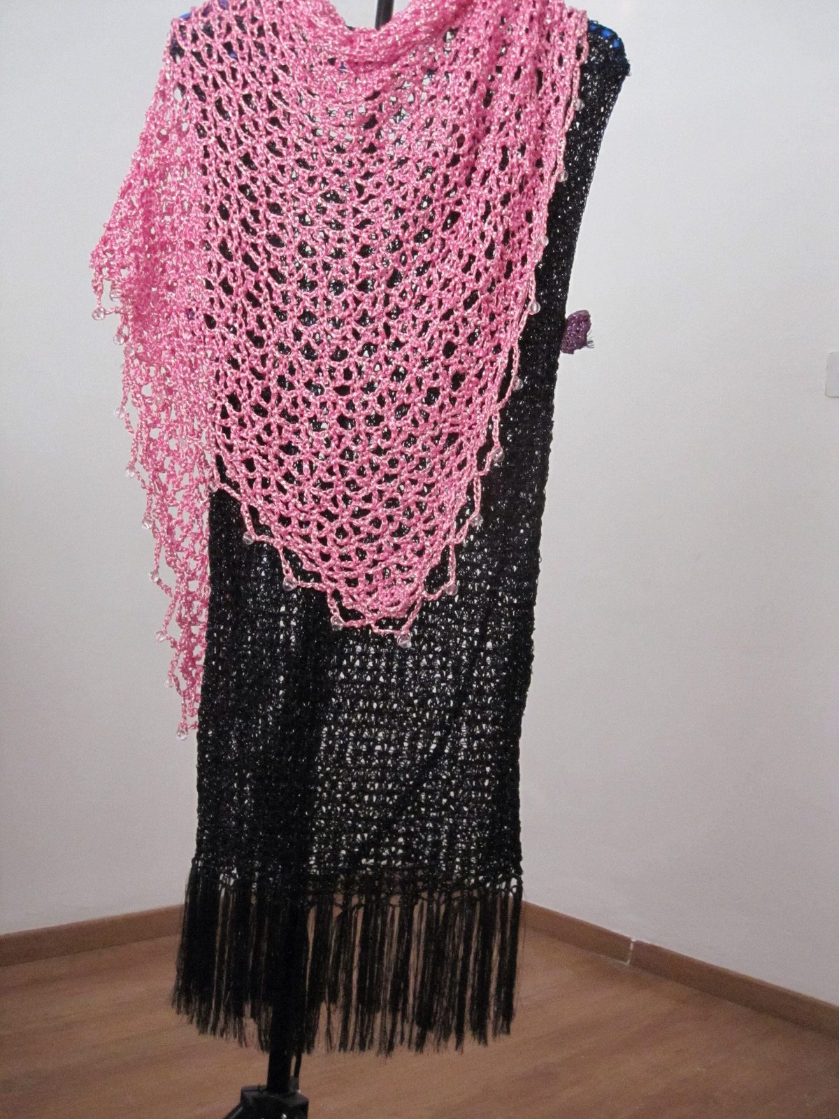 Pink shawl draped over a black fringed dress on a stand, front view of the sparkling wrap.