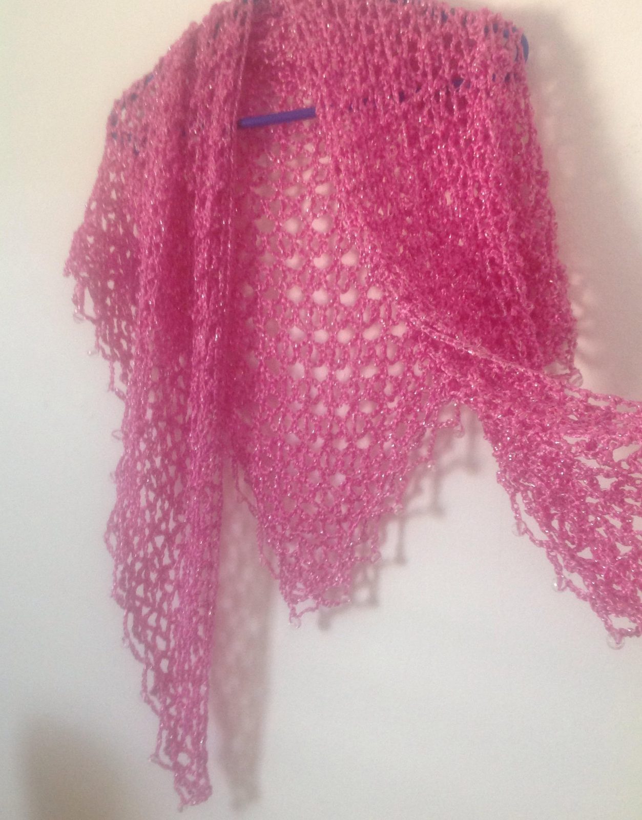 Pink shawl on a hanger folded into a soft cowl, view of the neckline drape.