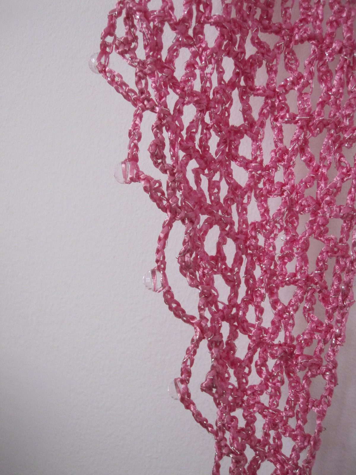 Close-up of the pink lurex crochet texture, glittering stitches in fine detail.
