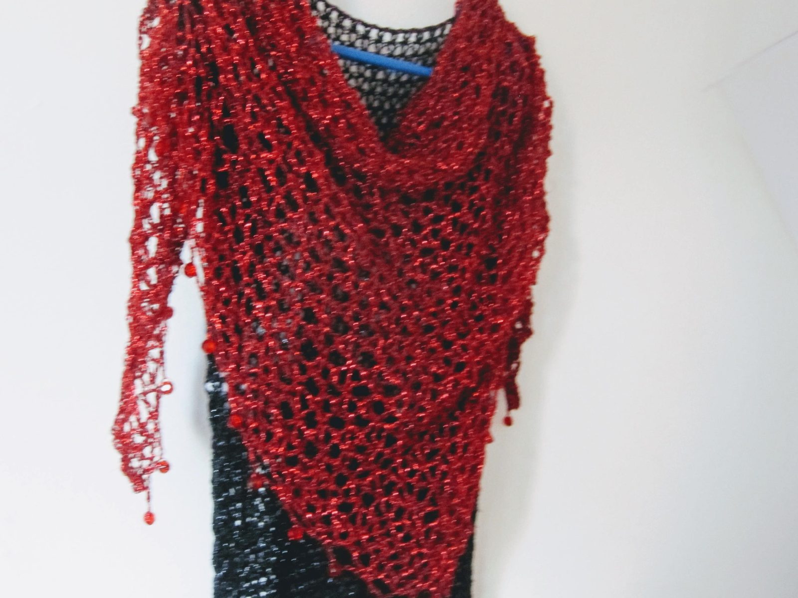 Red shawl over a black dress, closer view of the soft cowl neckline and airy crochet stitches.