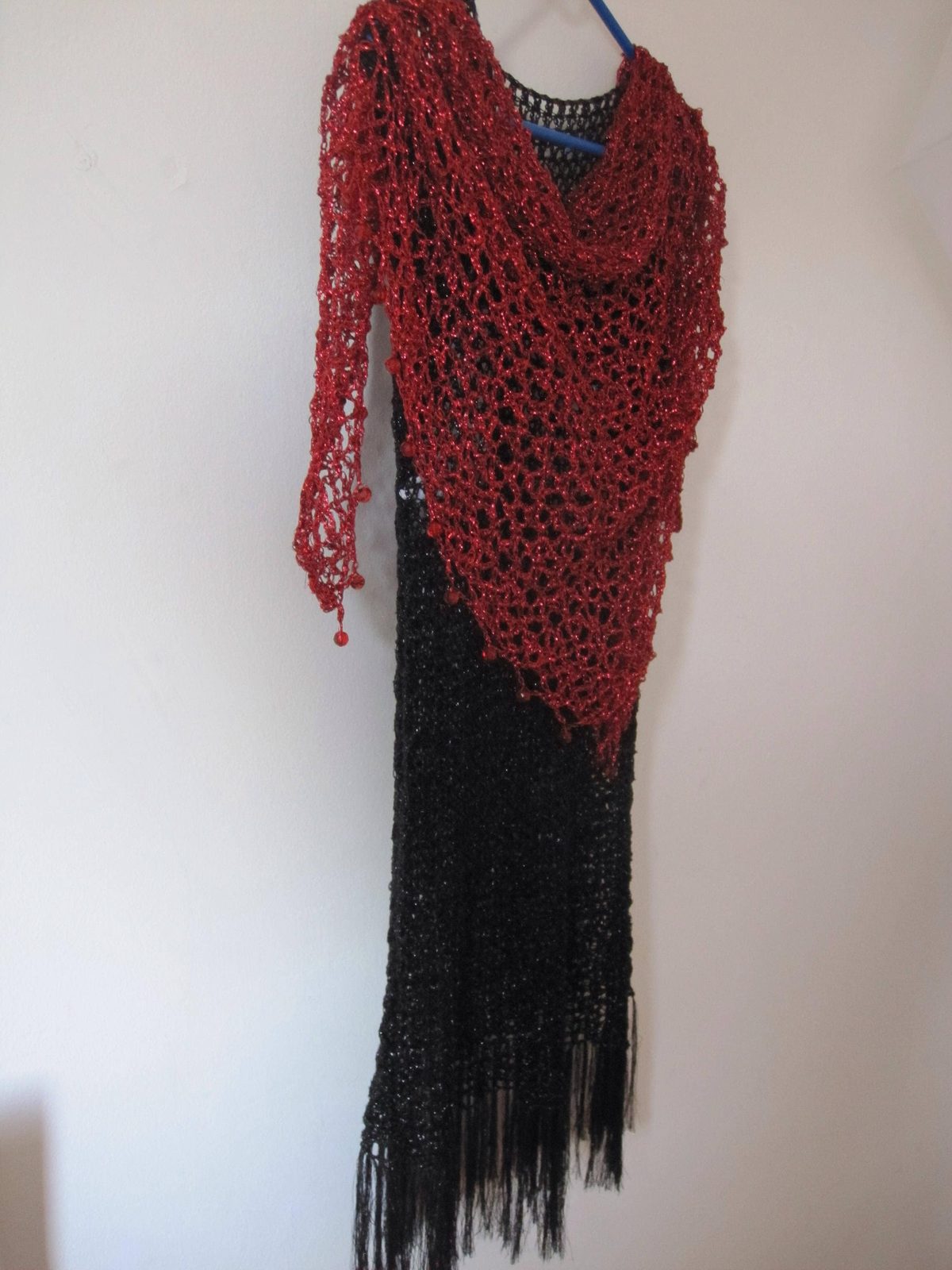 Red shawl over a black fringed dress, side angle showing the long flowing drape of the openwork.