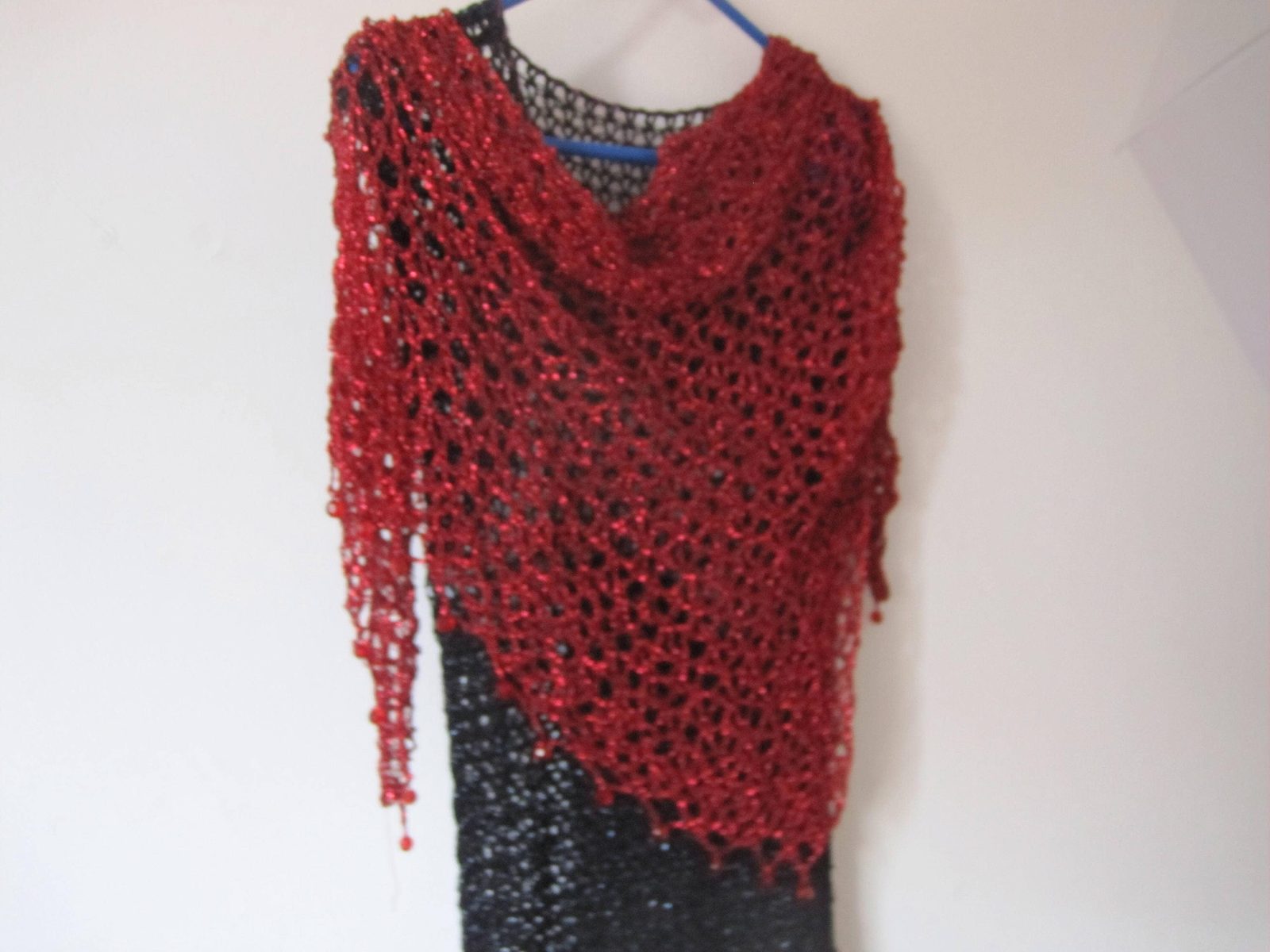 Red lurex shawl on a black dress, alternate front view of the openwork wrap and beaded edging.