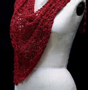 Red crochet shawl draped on a mannequin's torso, front view of the sparkling wrap.