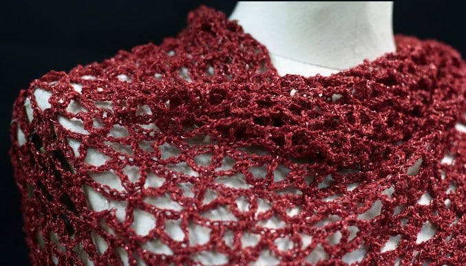Close-up of the red lurex openwork, revealing the texture of the hand-crocheted stitches.