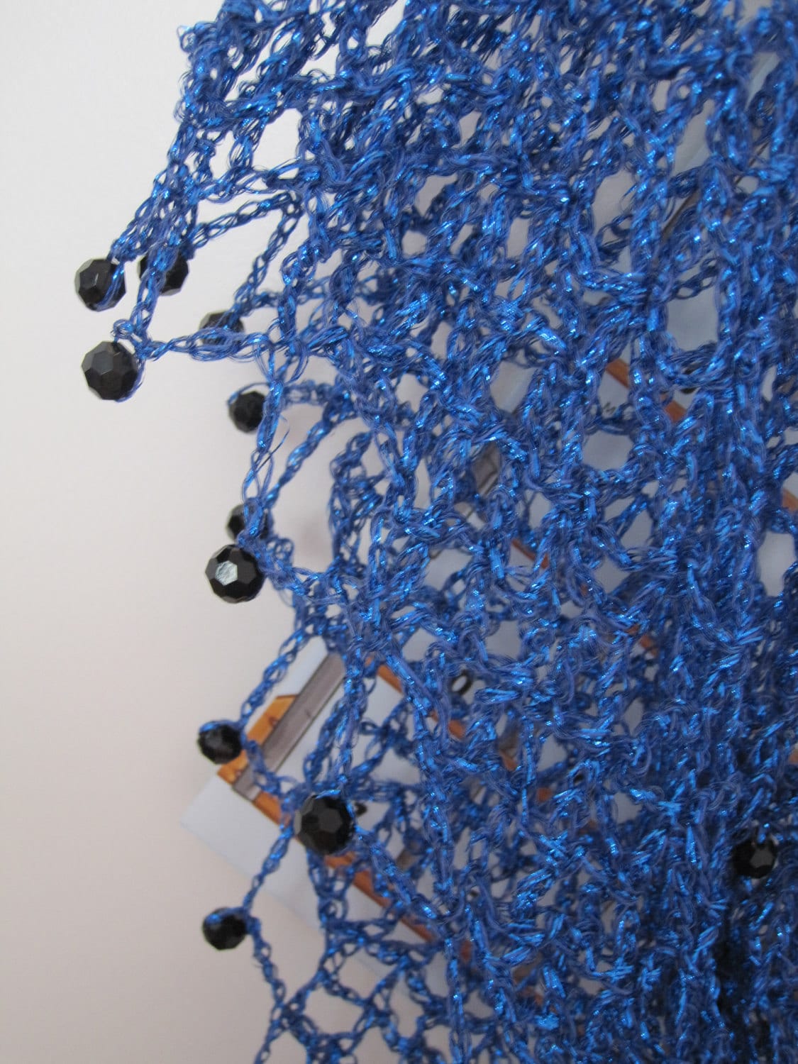 Close-up of the sapphire shawl's edge, dark beads hanging from the bright blue crochet.