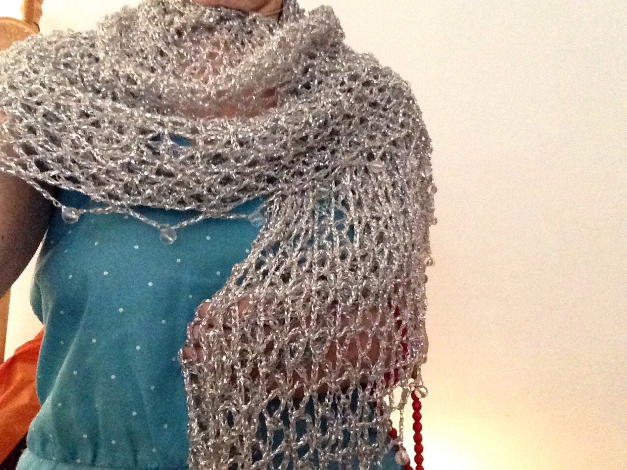 Silver lurex shawl wrapped around the neck and shoulders over a teal dress, highlighting the beaded trim along the edge.