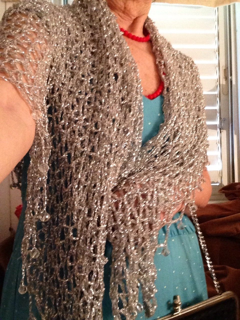 Side view of a woman in a silver lurex shawl over a turquoise dress, the wrap cascading past her waist.
