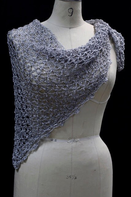 Lightweight silver-white shawl draped on a dress-form mannequin against a dark background, front three-quarter view.