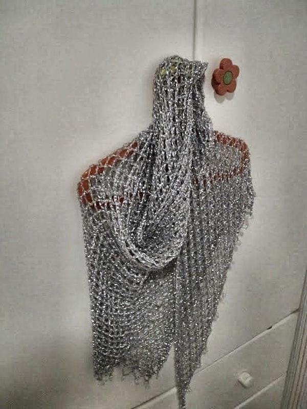 Silver beaded lurex shawl hanging on a red hanger against a white door, folded into a soft cowl drape.