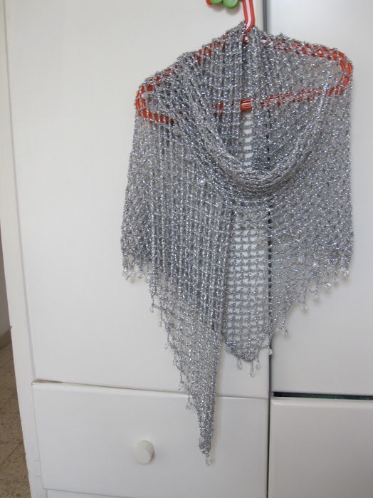 Silver beaded shawl on a red hanger against white closet doors, draped to a long point.