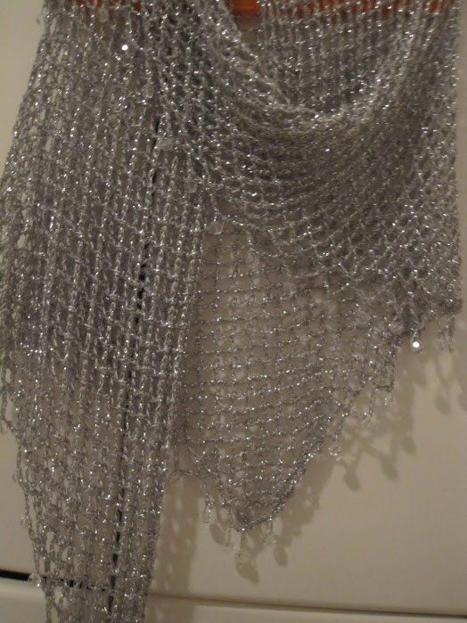 Close-up of the silver lurex shawl texture, showing dense hand stitches, fine beads, and metallic sheen along the hem.