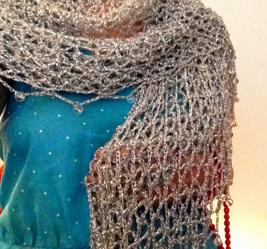Silver shawl over a turquoise dress, closer view of the cowl neckline and openwork stitches.