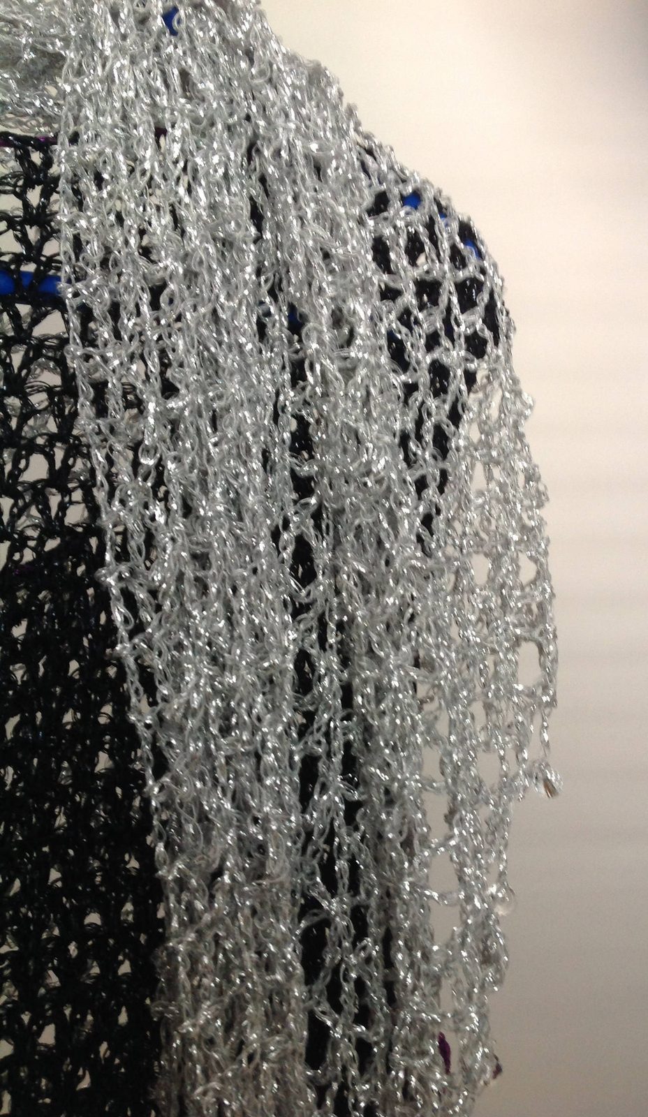 Close-up of the silver lurex crochet texture, revealing tight hand stitches, fine beads, and metallic sparkle.