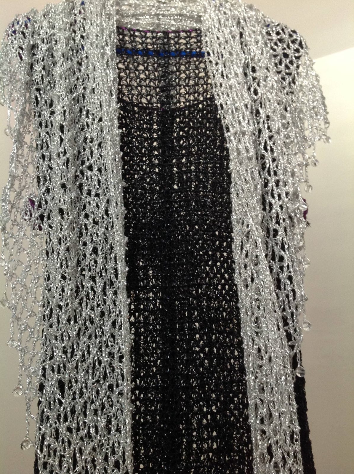Silver beaded lurex shawl arranged over a black dress, front view of the openwork wrap and beaded edging.