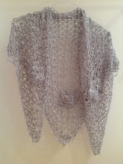 Silver floral shawl hanging flat on a hanger, full view of the openwork and scattered flower motifs.