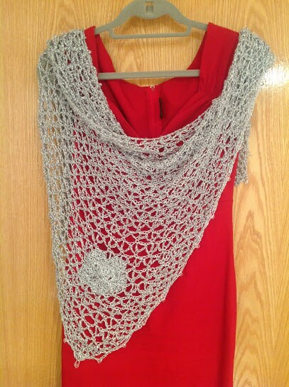 Silver floral shawl draped over a red dress on a hanger, front view with a flower applique visible.