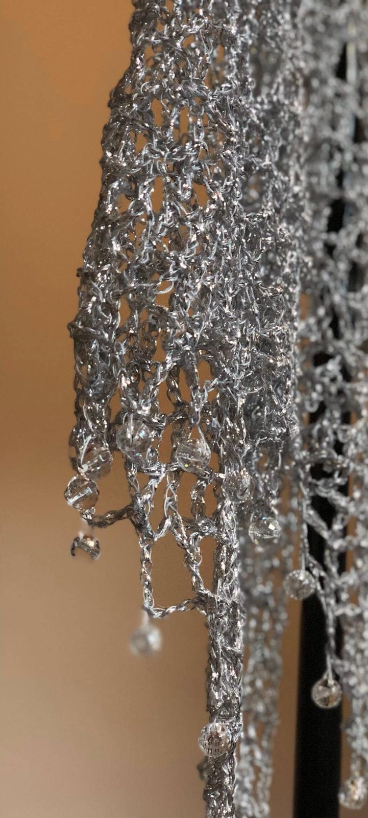 Close view of the silver shawl's beaded fringe edge, with dangling beads along the scalloped trim.
