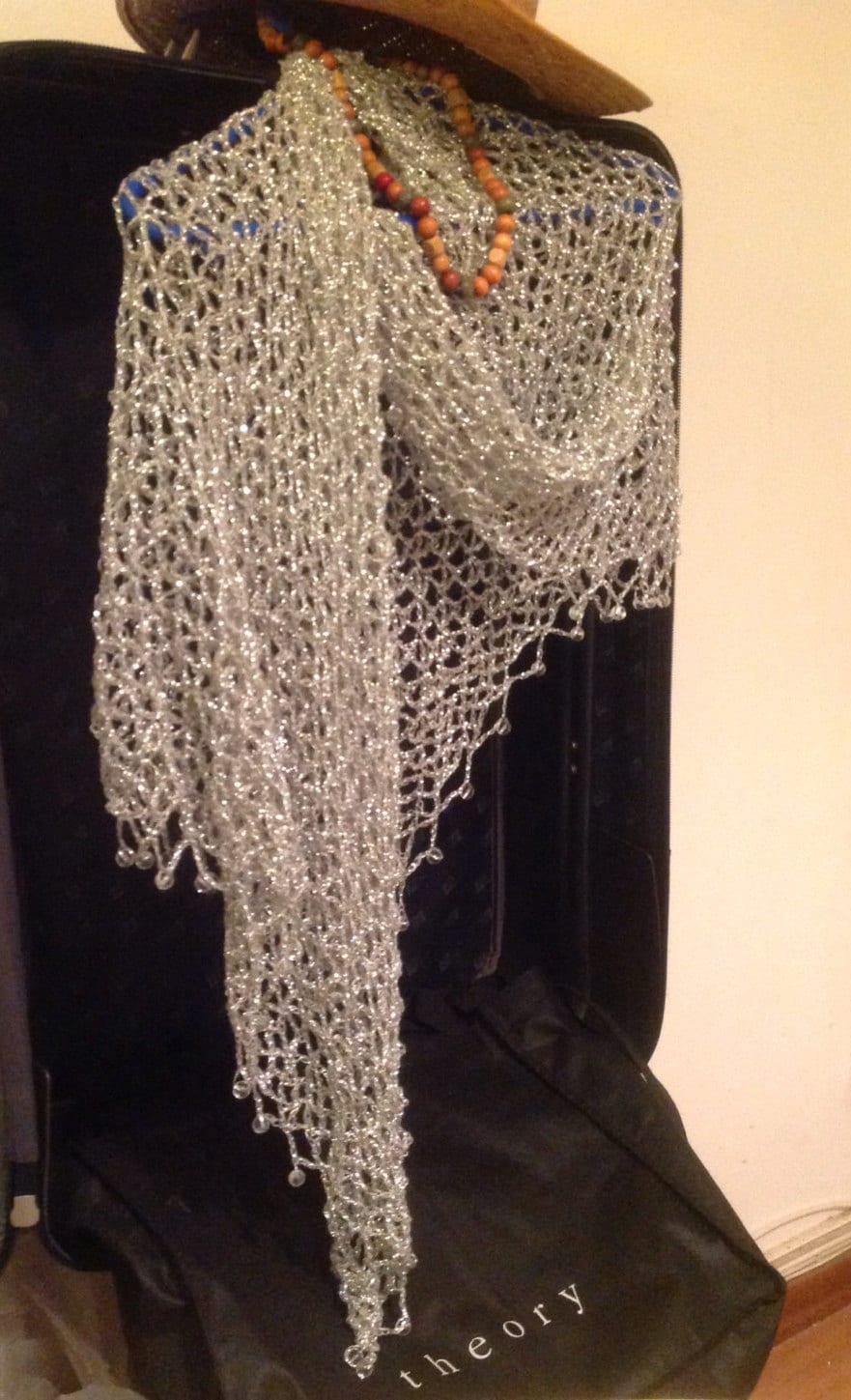 Silver beaded shawl over a dark garment with a beaded necklace, front view of the shimmering drape.