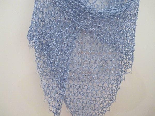 Sky blue lurex crochet shawl hanging in a full view, delicate openwork catching the light.