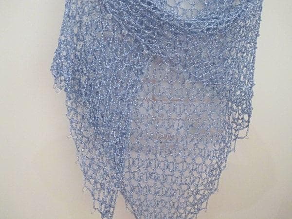 Sky blue lurex crochet shawl hanging in a full view, delicate openwork catching the light.