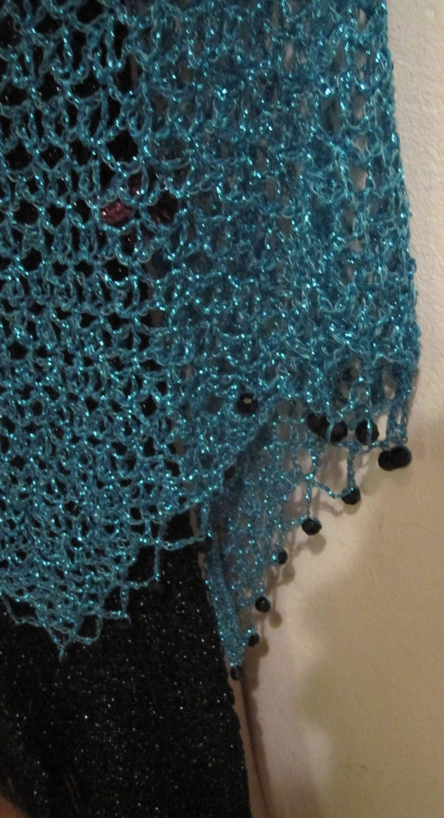 Close-up of the turquoise lurex crochet, revealing tight hand stitches and dark beads along the scalloped edge.