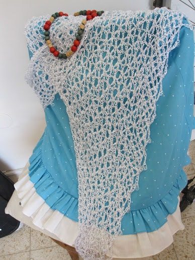 White lurex shawl draped over a turquoise ruffled dress, styled with a colorful beaded necklace.